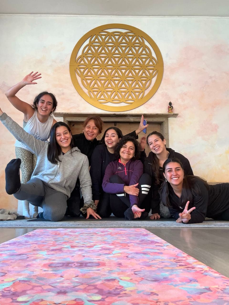 Grupo de alumnas posando con humor frente a un mandala dorado, después de la clase