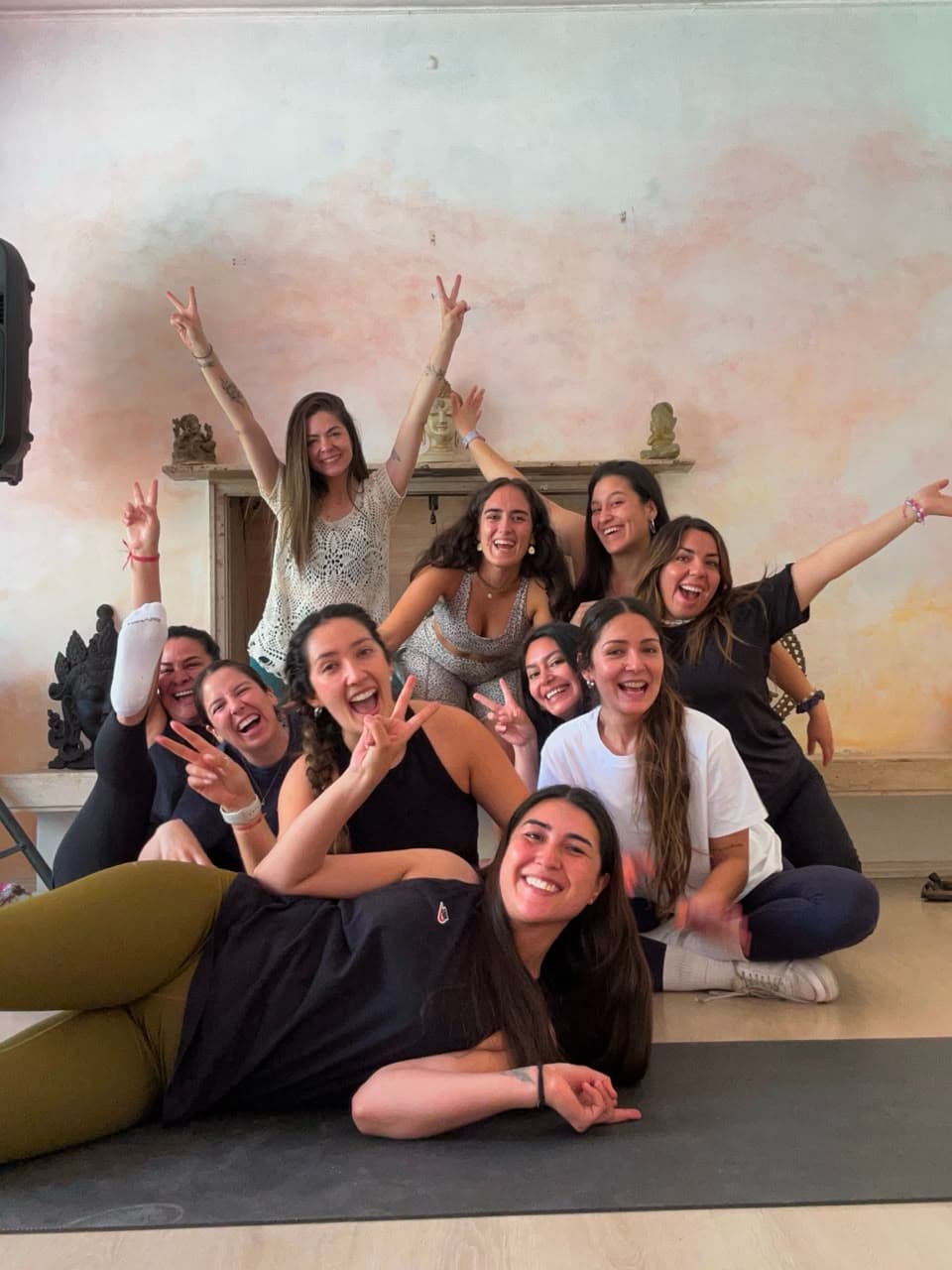 Grupo grande de alumnas sonriendo y haciendo señas de paz tras la clase