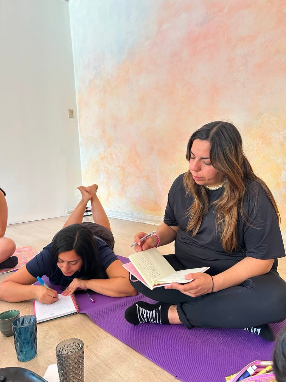Dos alumnas escribiendo en sus cuadernos sobre el mat, en un momento de reflexión